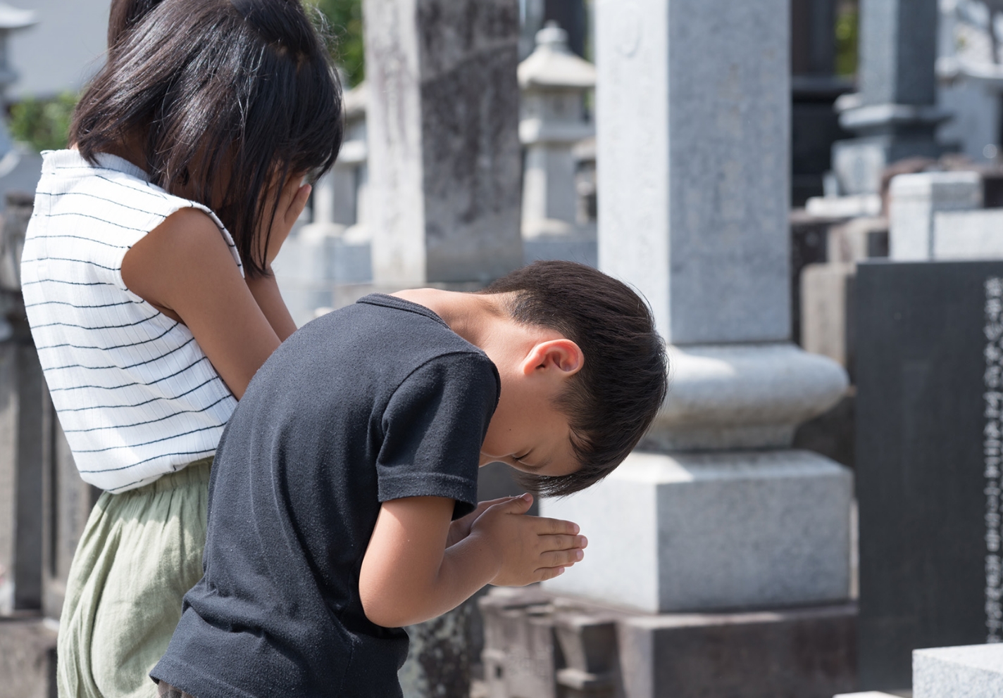 お墓に手を合わせる子供たち
